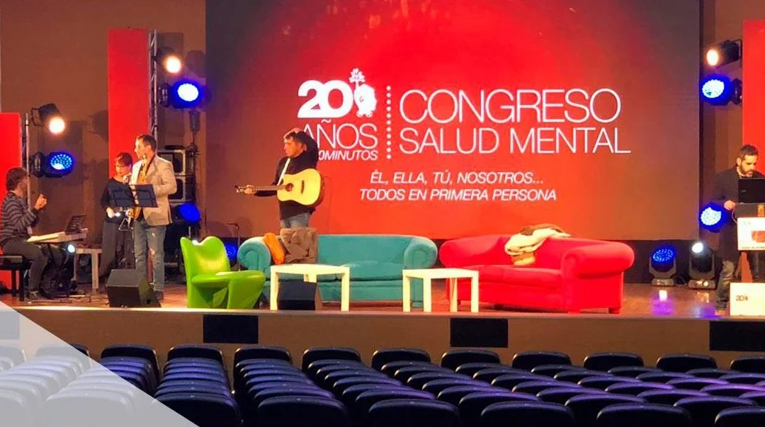 Escenario de un congreso con una pantalla LED de fondo mostrando la identidad del evento, con el patio de butacas en primer término